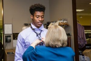 A young man getting fitted for a suit by east valley women's league