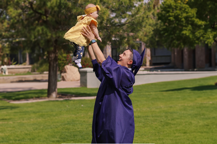 a teen parent celebrating graduation with his baby
